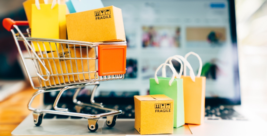 Product package boxes and shopping bag in cart with laptop computer which web store shop on screen for online shopping and delivery concept