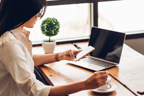 Frau sucht via AMS Berufsinfomat Arbeit (sitzend vor einem offenen Notebook)