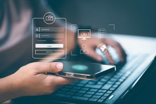 Rechte Hand mit Smartphone für Fingerdruck-ID (biometrische Authentifizierung) und linke Hand auf Laptop-Tastatur
