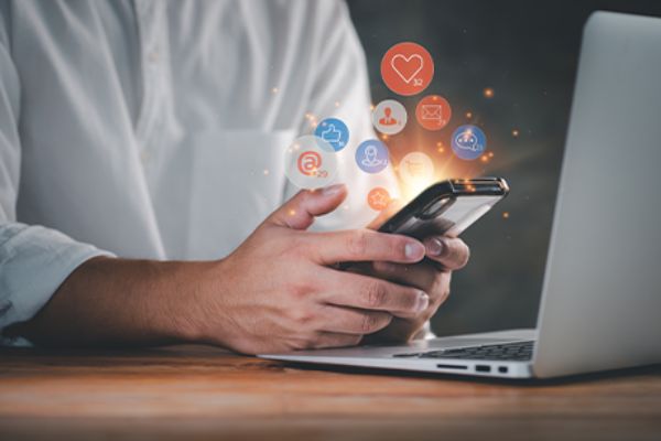 Männlicher Torso vor Smartphone und offenem Laptop