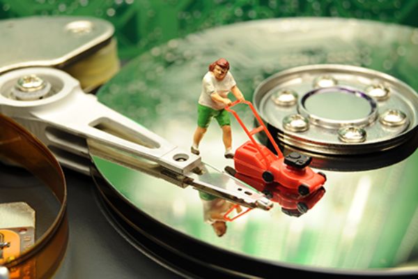 Figur, mit Rasenmäher steht auf einer Computerfestplatte