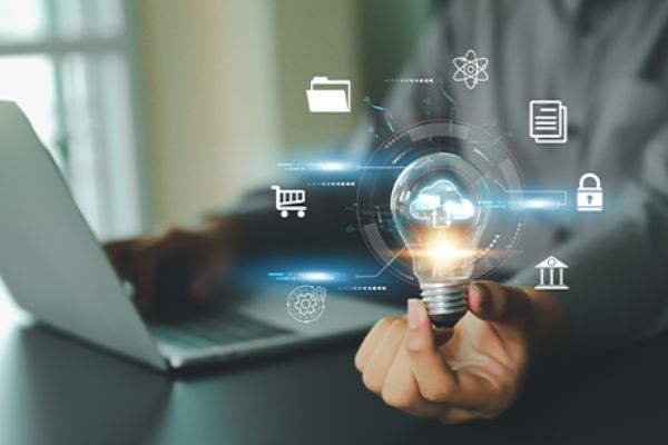Glühbirne mit Cloudsymbol darin von linker Hand gehalten vor offenem Notebook