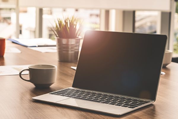 Tasse und Laptop auf Tisch
