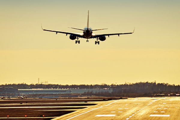 Flugzeug über Landebahn vor sonnigem Himmel