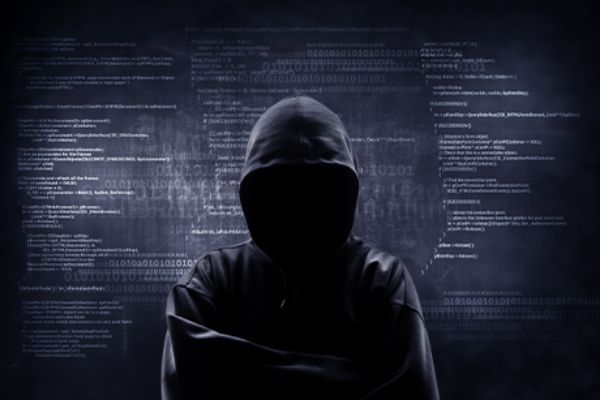 Hacker mit schwarzer Kapuze vor schwarzem Hintergrund