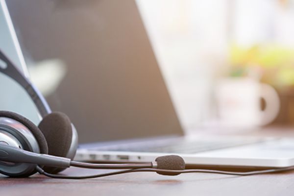 neben einem aufgeklappten Laptop liegen Headsets