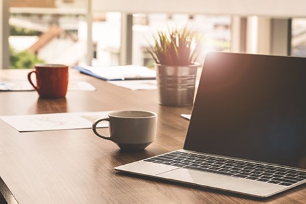Laptop mit Kaffeehäferl auf Tisch