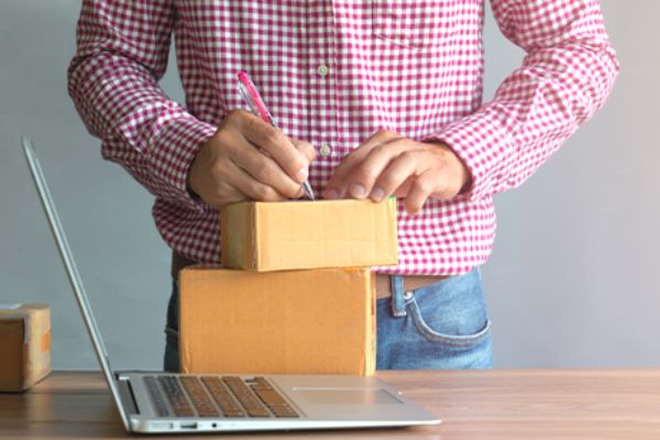 Torso vor einem Tisch mit Paketen und Laptop