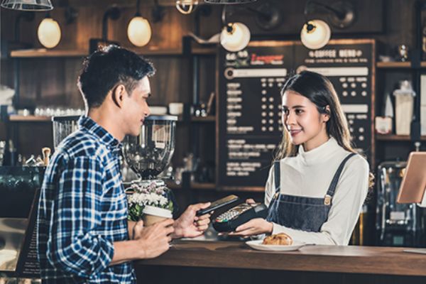 Mann bezahlt an Café Theke mit seinem Handy via NFC