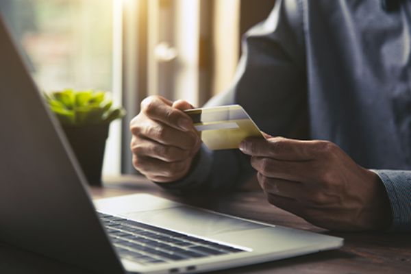Daten-Monetarisierung: Mann hält Bankkarte vor offenem Notebook