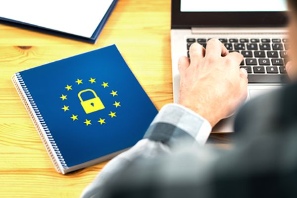 Rückenansicht Mann vor Notebook und Mappe mit DSGVO-Symbol