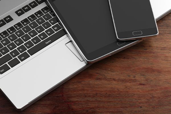 Smartphone liegt auf Tablet liegt auf Laptop-Tastatur