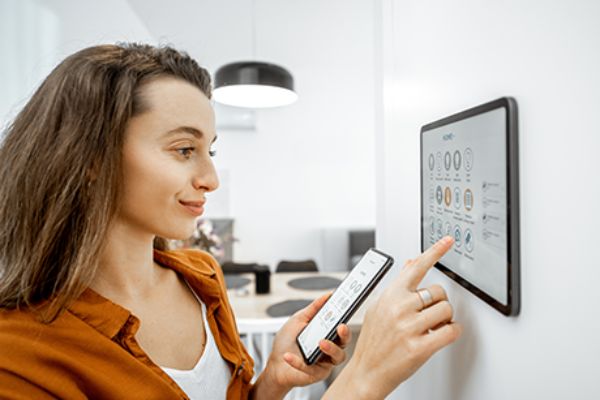 Frau steuert Smart Home am Tablet und Smartphone