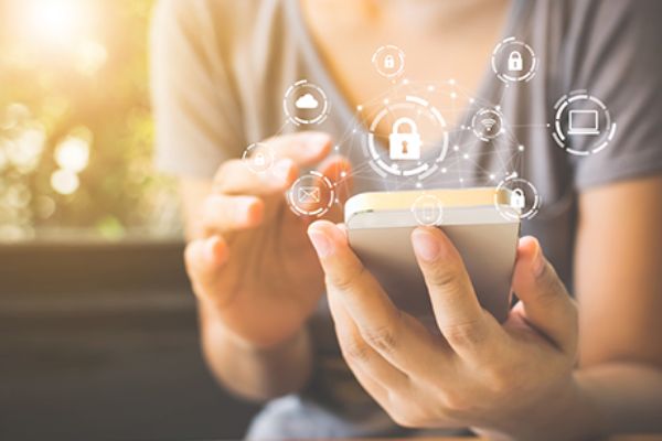 Junge Frau hält Smartphone in den Händen mit Security Symbolen darüber
