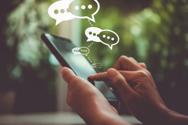 Threads: textbasiertes Social Media (Symbolbild mit Chatblasen über Smartphone)