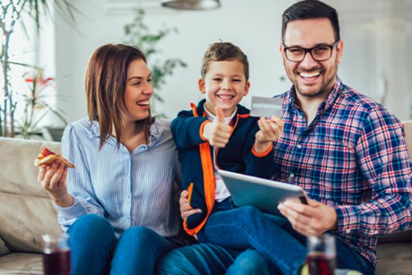 Familie auf einem Sofa beim Online-Shopping mit Tablet 