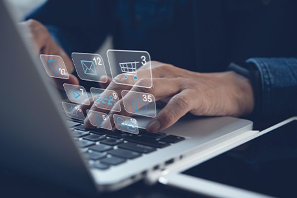 Werbung im Netz: Offenes Notebook mit eCommerce-Symbolen über der Tastatur