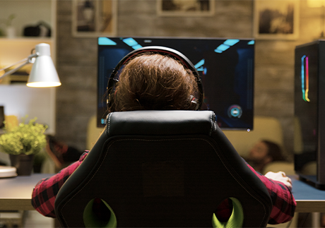 Rückansicht: Teenager sitz vor einem Gaming-Computer