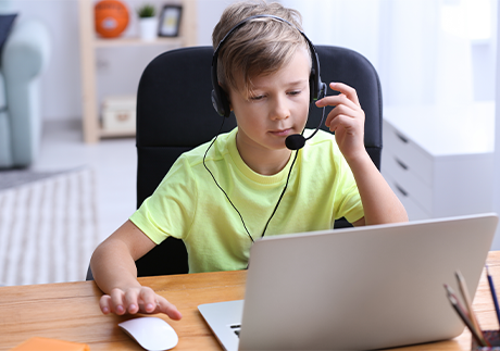 Junge mit Headset sitzt vor Laptop.