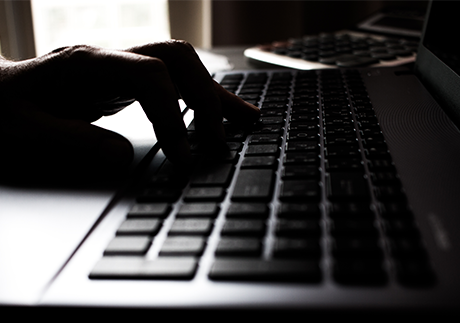 Hand tippt im Dunklen auf Laptop-Tastatur