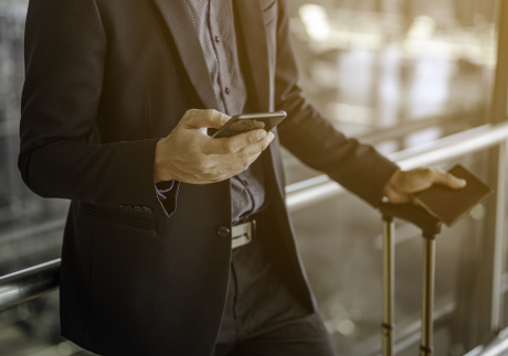 Businessman using mobile phone at the airport. holding passport with luggage.Travel and business airport concept.