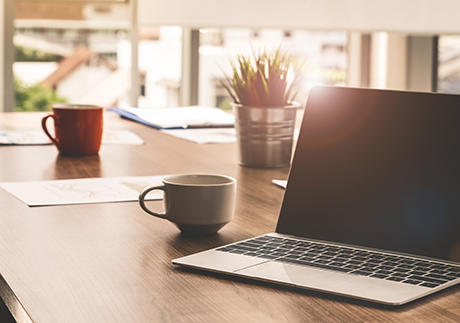 Laptop mit Kaffeehäferl auf Tisch