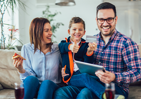 Familie auf einem Sofa beim Online-Shopping mit Tablet 