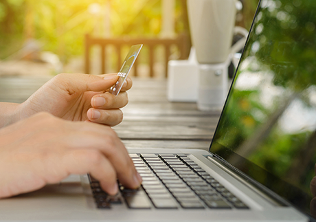 Mensch shoppt online am Laptop