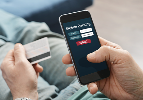 Hände halten Smartphone und Bankkarte in Nahansicht.
