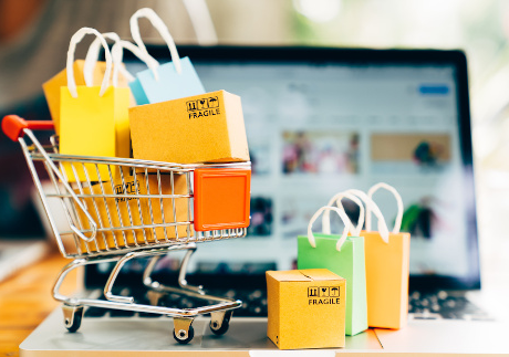 Product package boxes and shopping bag in cart with laptop computer which web store shop on screen for online shopping and delivery concept