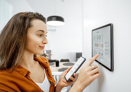 Frau steuert Smart Home am Tablet und Smartphone