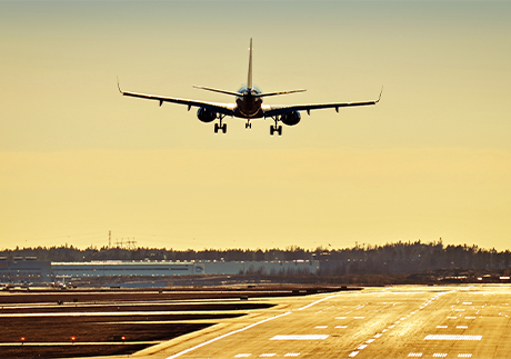 Flugzeug über Landebahn vor sonnigem Himmel