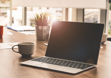 Tasse und Laptop auf Tisch